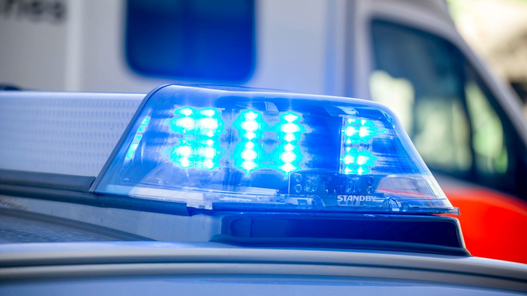 Foto: Blaulicht eines Polizeiwagen vor einem Fahrzeug des Rettungsdienstes